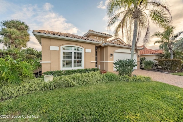 mediterranean / spanish home featuring a yard and a garage