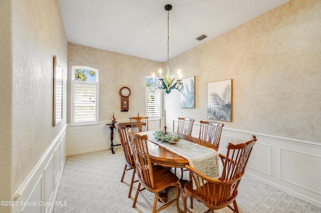 5601 Sea Lavender Pl, Melbourne Beach, FL 32951 - dining area featuring a decorative wall, a chandelier, a wainscoted wall, and light carpet