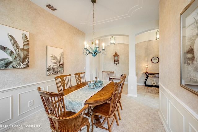 5601 Sea Lavender Pl, Melbourne Beach, FL 32951 - dining area with a chandelier, wainscoting, light colored carpet, and arched walkways