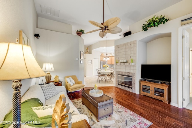 5601 Sea Lavender Pl, Melbourne Beach, FL 32951 - living room featuring a ceiling fan, wood finished floors, lofted ceiling, a tiled fireplace, and a chandelier