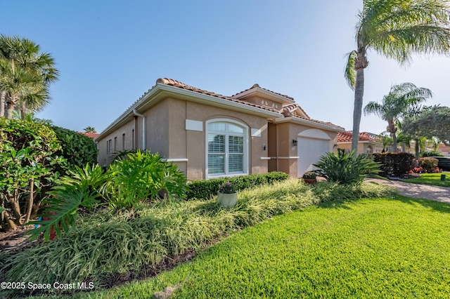 5601 Sea Lavender Pl, Melbourne Beach, FL 32951 - mediterranean / spanish-style house with a front yard, stucco siding, an attached garage, and a tiled roof