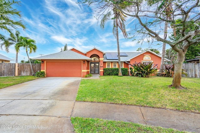 ranch-style home featuring a front lawn, a garage, and solar panels