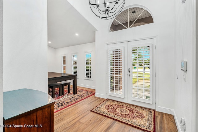 foyer with a wealth of natural light, french doors, a towering ceiling, and hardwood / wood-style floors