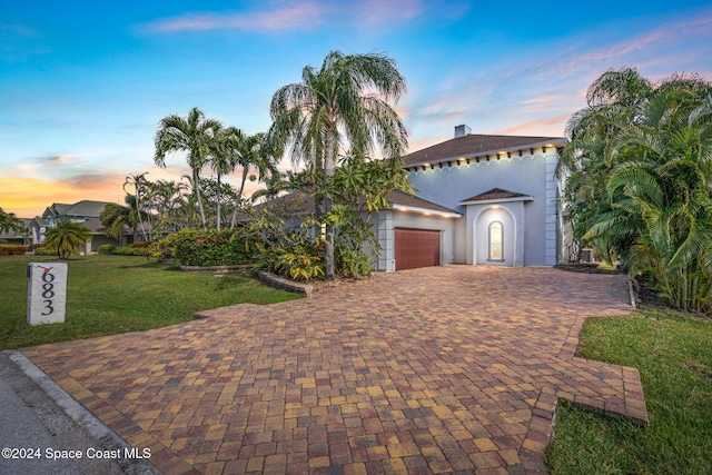 mediterranean / spanish-style home with a lawn and a garage