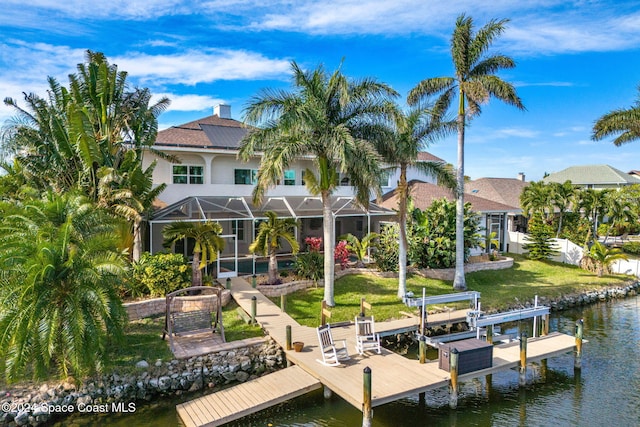 view of dock with a water view, a lanai, and a lawn