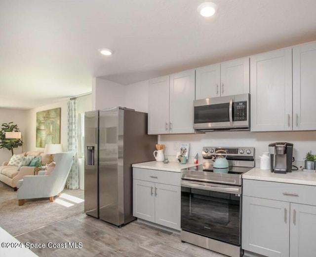 kitchen featuring light wood-type flooring, stainless steel appliances, and white cabinetry