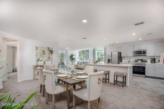 dining room featuring light colored carpet and a textured ceiling