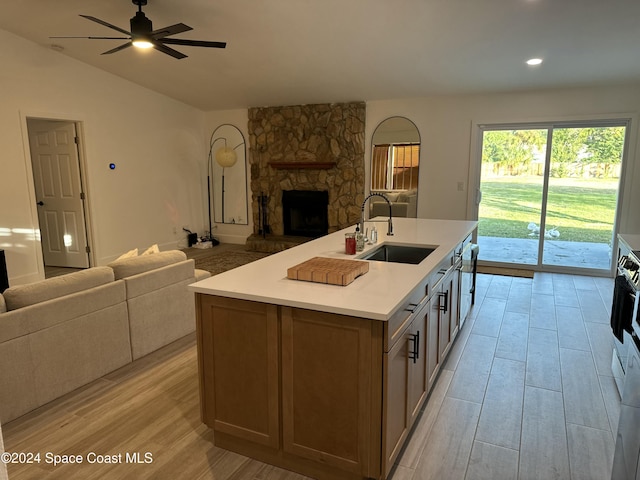 kitchen featuring a fireplace, light hardwood / wood-style floors, sink, and a kitchen island with sink