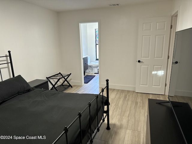 bedroom with ensuite bath and light hardwood / wood-style flooring