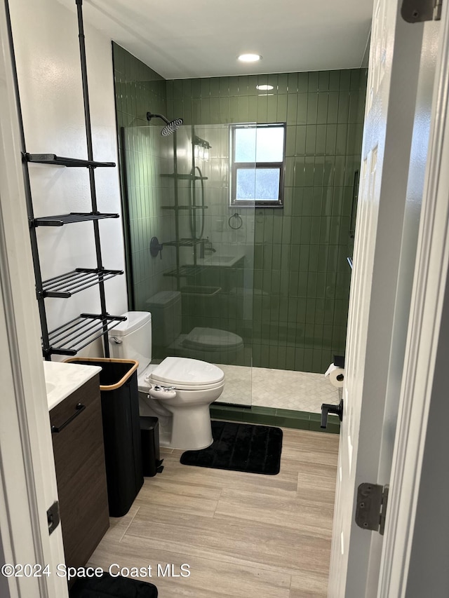 bathroom featuring a tile shower, vanity, and toilet