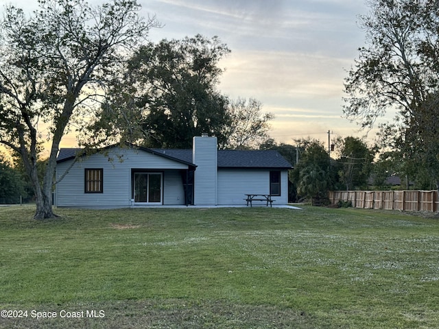 back house at dusk featuring a yard