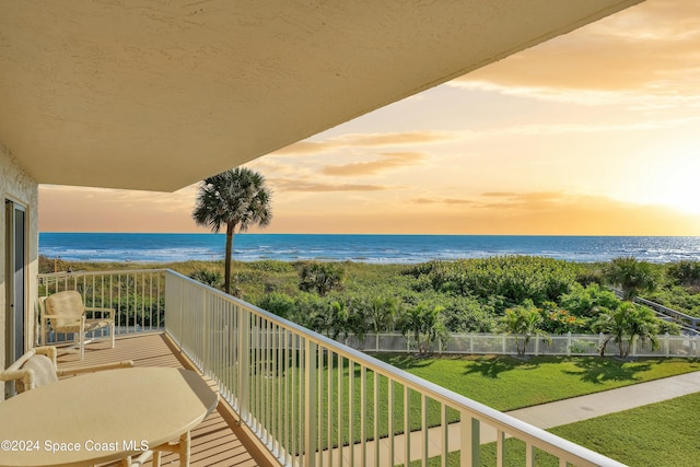 balcony at dusk with a water view and a beach view