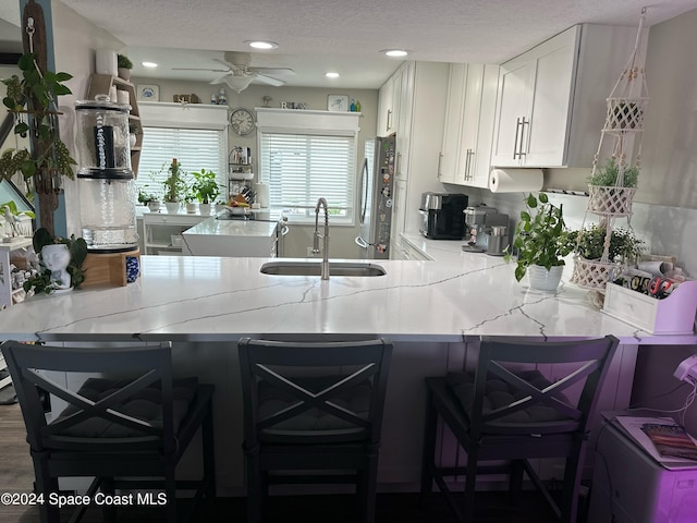 kitchen with kitchen peninsula, stainless steel refrigerator, sink, and a breakfast bar