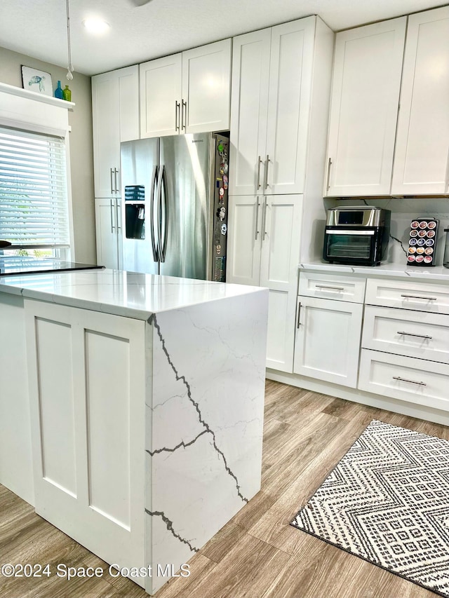 kitchen featuring white cabinetry, light stone counters, light hardwood / wood-style floors, and stainless steel refrigerator with ice dispenser