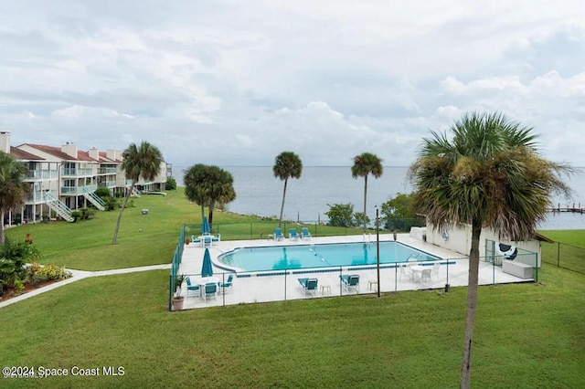 view of swimming pool featuring a patio, a water view, and a lawn