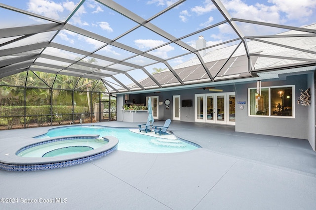 view of pool featuring glass enclosure, an in ground hot tub, a patio, and french doors