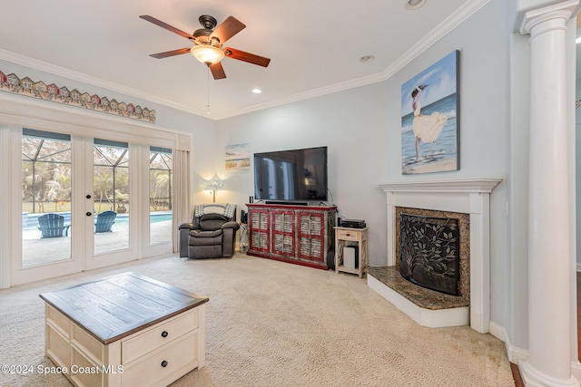 carpeted living room featuring a high end fireplace, french doors, decorative columns, ornamental molding, and ceiling fan