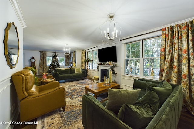 living room with crown molding, plenty of natural light, and an inviting chandelier