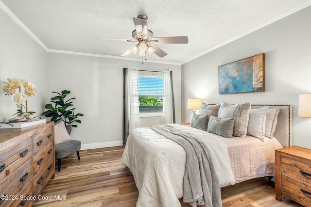 bedroom featuring ceiling fan, light hardwood / wood-style flooring, a textured ceiling, and ornamental molding