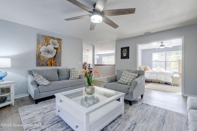 living room with ceiling fan, a textured ceiling, and hardwood / wood-style flooring