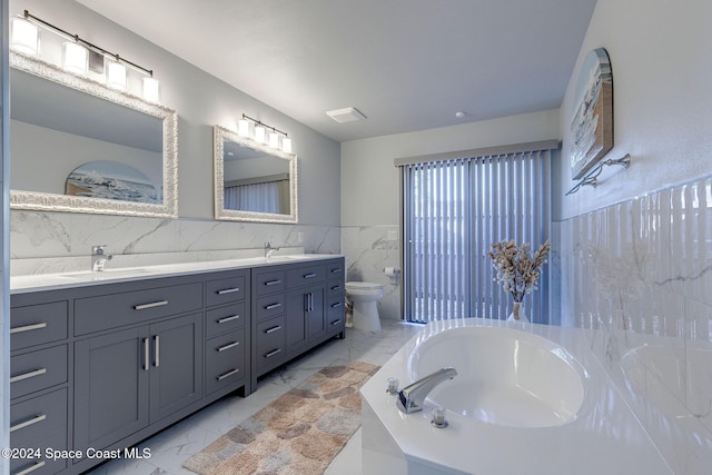 bathroom with vanity, toilet, a tub to relax in, and tile walls