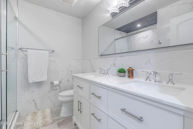 bathroom with an enclosed shower, vanity, toilet, and tile walls