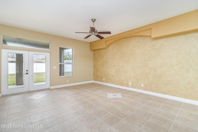 tiled spare room featuring ceiling fan and french doors