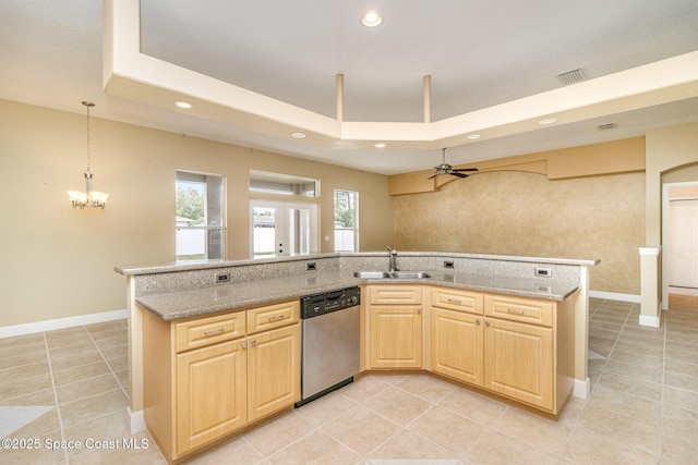 kitchen featuring a tray ceiling, dishwasher, ceiling fan with notable chandelier, and sink