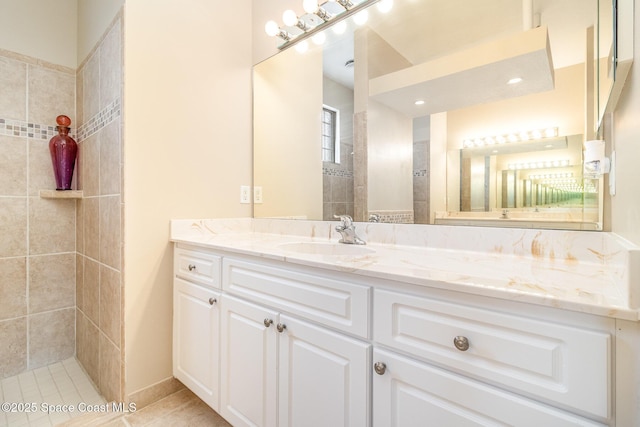 bathroom featuring tile patterned flooring, vanity, and a tile shower