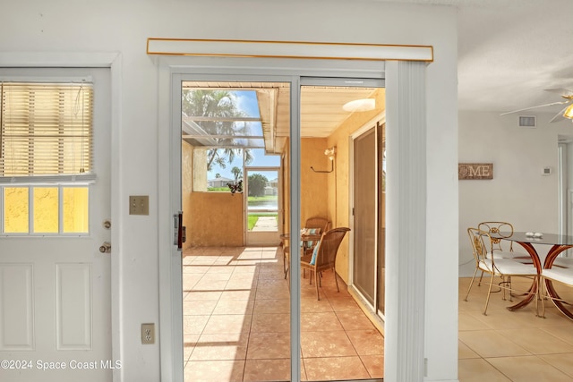 doorway featuring ceiling fan and light tile patterned floors