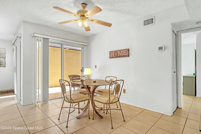 tiled dining room with ceiling fan and a textured ceiling