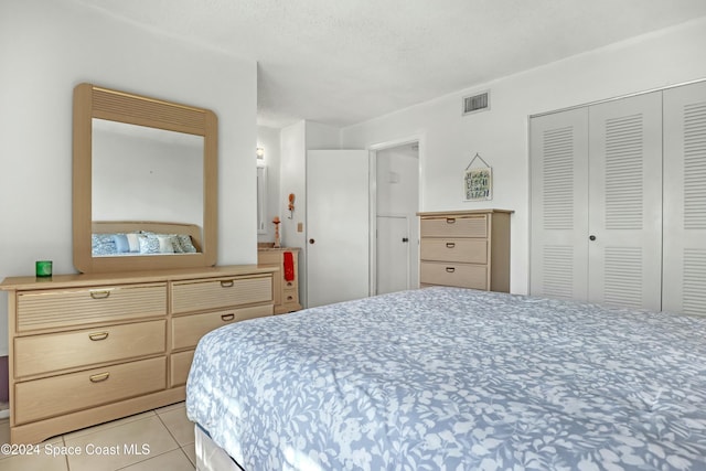 tiled bedroom with a textured ceiling and a closet