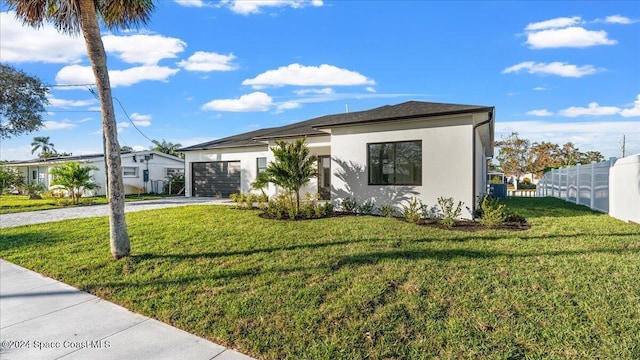 view of front facade with an attached garage, fence, driveway, stucco siding, and a front yard