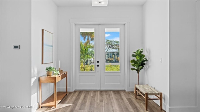 doorway with french doors, wood finished floors, and baseboards