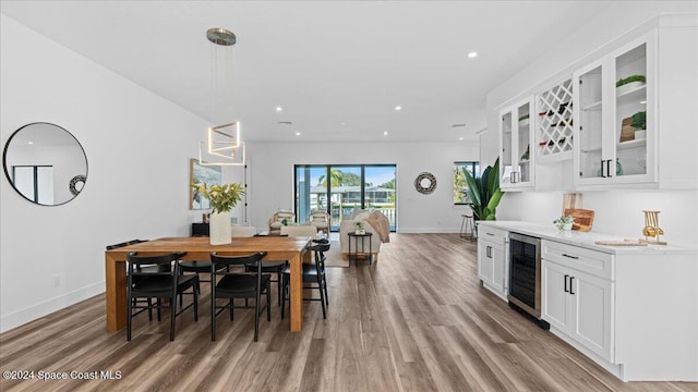 dining space featuring recessed lighting, beverage cooler, baseboards, light wood-style floors, and a bar