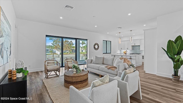 living area featuring baseboards, wood finished floors, visible vents, and recessed lighting