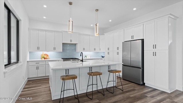 kitchen with dark wood-style flooring, light countertops, freestanding refrigerator, white cabinets, and a sink