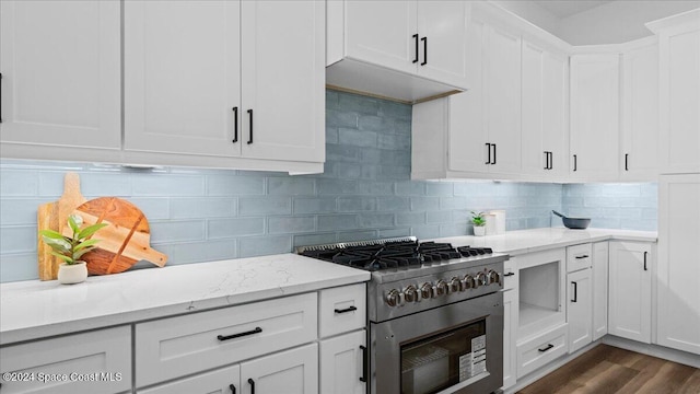 kitchen with dark wood-style flooring, tasteful backsplash, stainless steel range, and white cabinetry