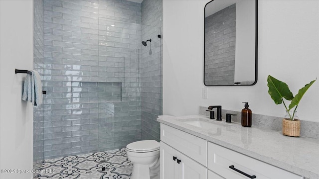 bathroom with tiled shower, vanity, and toilet