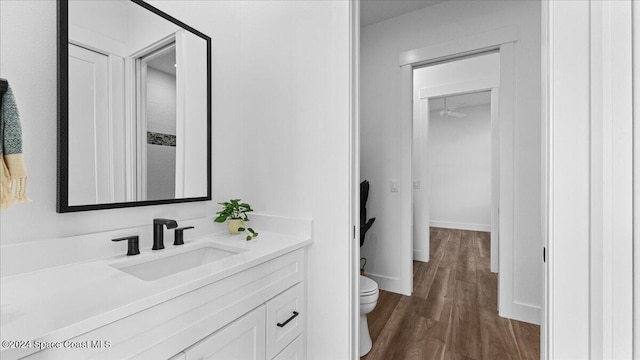 bathroom with wood finished floors, vanity, toilet, and baseboards