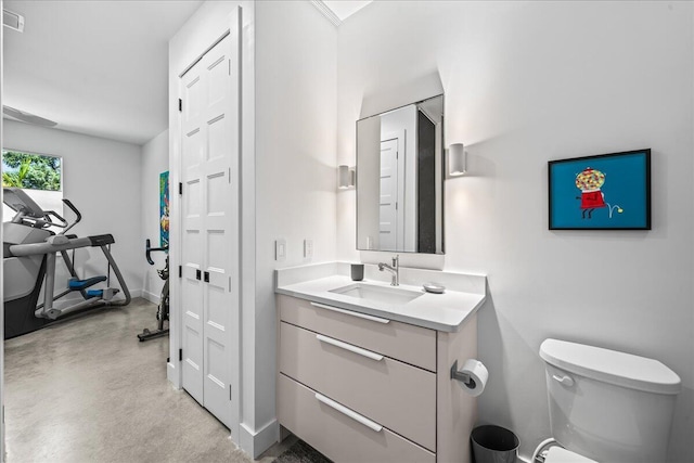 bathroom with concrete flooring, vanity, and toilet