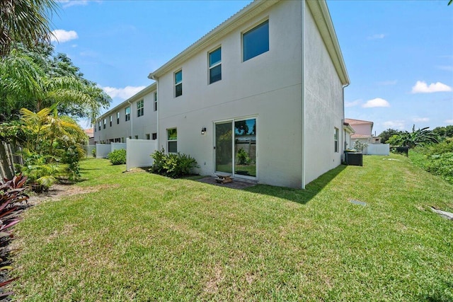 rear view of property featuring a lawn and cooling unit