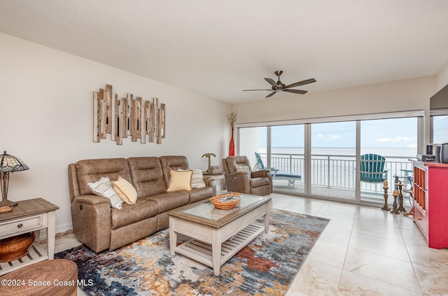 living room featuring ceiling fan, a water view, and light tile patterned flooring