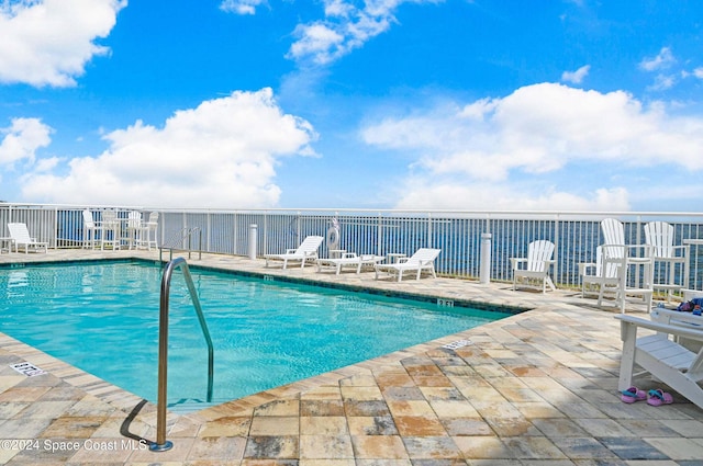 view of pool with a patio and a water view