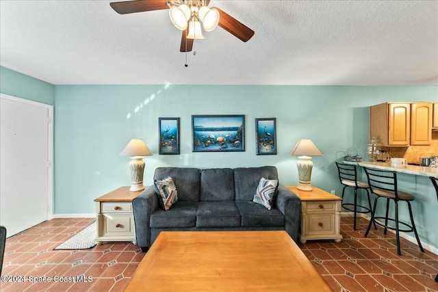 living room with a textured ceiling, dark tile patterned flooring, and ceiling fan