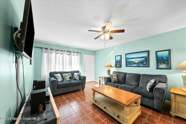 living room featuring ceiling fan, dark tile patterned floors, and a textured ceiling