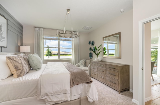 carpeted bedroom with access to exterior, an inviting chandelier, and multiple windows