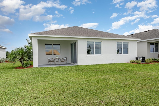 rear view of property featuring central AC unit, a yard, and a patio