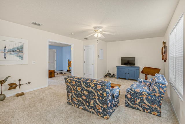 carpeted living room with a textured ceiling and ceiling fan