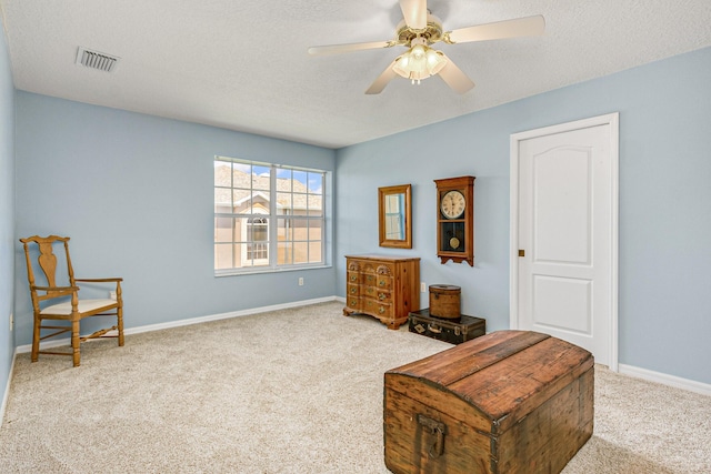 living area featuring light carpet, a textured ceiling, and ceiling fan